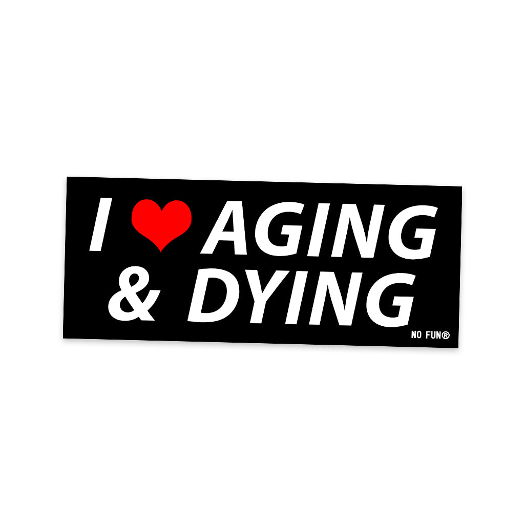 The original "Aging and Dying" Bumper sticker. Item is black, with white text that reads "I ❤️Aging & Dying". The heart is red, and there is a small white No Fun® logo in the bottom right corner.