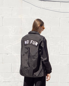 Photo of a female model wearing the "NO FUN®" X "Crawling Death" collaboration coaches jacket.  The model is showcasing the extra large "NO FUN®" logo back patch which is found on the back of the jacket.