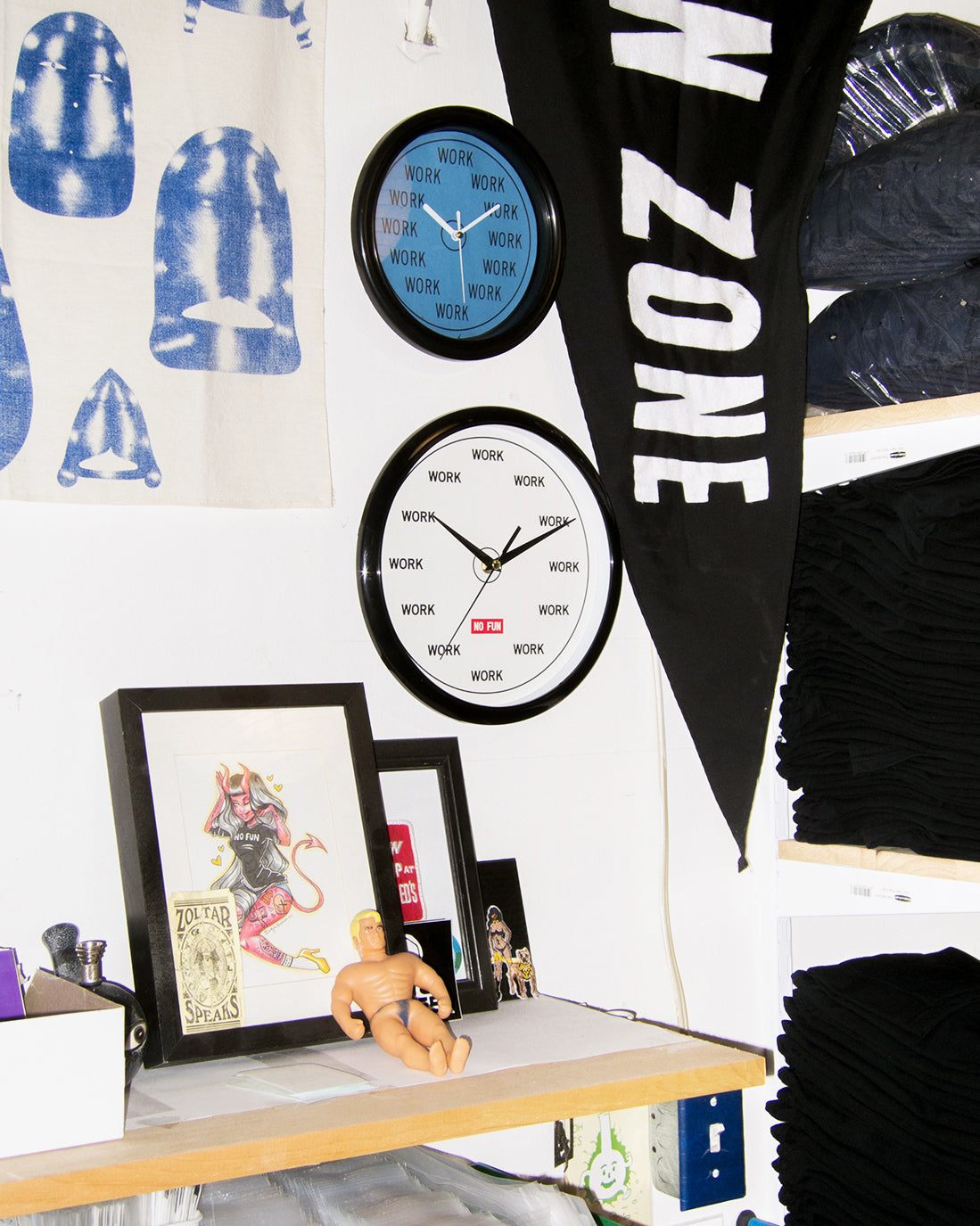 The original "WORK" studio wall clock. Wall clock with "WORK" replacing the hours/minutes on the face. Red No Fun® logo in center. Clock is photographed on a pegboard, surrounded by various framed photos, prints, and toys.