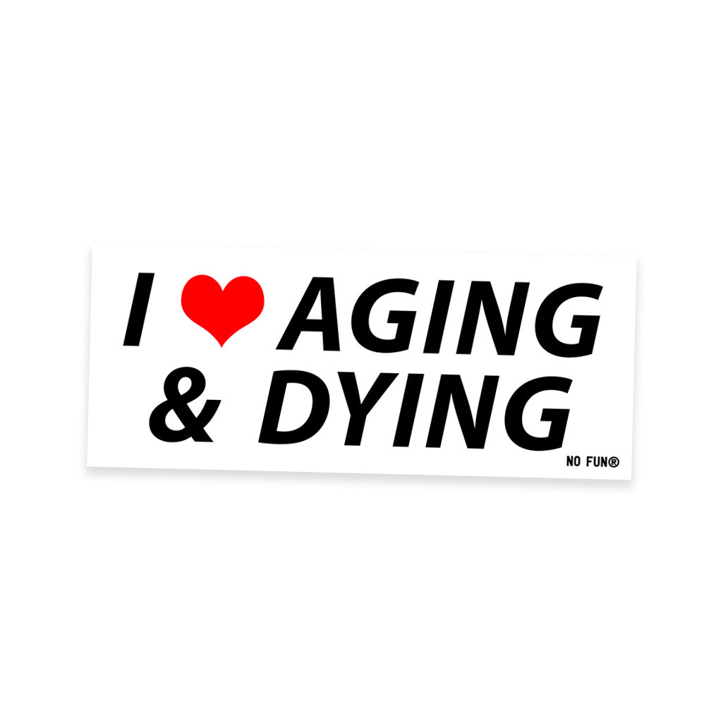 The original "Aging and Dying" Bumper sticker.  Item is white, with black text that reads "I ❤️Aging & Dying".  The heart is red, and there is a small black No Fun® logo in the bottom right corner.
