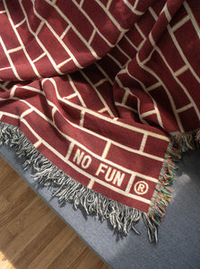 The "Brick" Woven Blanket by No Fun®.  The blanket is draped across a grey couch.