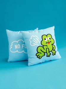 Two Frog Pillows by No Fun®.  The pillow in front has the side with the farting frog facing the camera, while the second pillow has its side with the logo is placed slightly behind it, just off to the left.  The pillows are against a blue background.