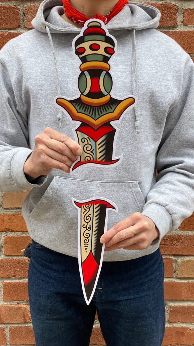 Image features the "No Fun®" sword PVC sign which was designed in collaboration with Brandon Ing.  It is a two part sign where one half is the blade, while the other is the handle.  The design is based off of traditional tattoo flash artwork.  The photo features the product being held by the artist, against his torso to show scale of the product.