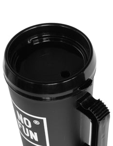 The "Big Sipper" Mug by No Fun® in the colour Black. The image is a close up view of the lid which is Black. The lid features a hole for a straw, as well as a small opening for drinking. The handle can be seen in the photo, as well as the square "No Fun®" logo that is printed in white. The mug is photographed against a white background.