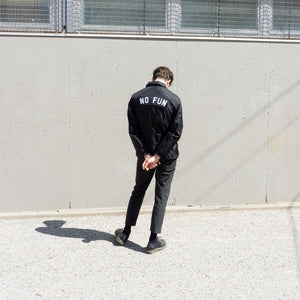 Photo of a male model wearing the "NO FUN®" X "Crawling Death" collaboration coatches jacket.  The model is showcasing the back of the jacket that features an extra large "NO FUN®" rocker back patch.  The patch is black with embroidered white logo.