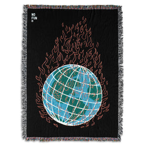 The "Global Warming" Woven Blanket by No Fun®.  The blanket is black, and features a globe in the center engulfed in flames.  The globe is blue and green, and the flames are red.  There is a small "No Fun®" logo found in the top left hand corner of the product.