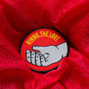 The "Gimme the Loot" patch on red perforated fabric.