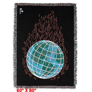 The "Global Warming" Woven Blanket by No Fun®. The blanket is black, and features a globe in the center engulfed in flames. The globe is blue and green, and the flames are red. There is a small "No Fun®" logo found in the top left hand corner of the product.