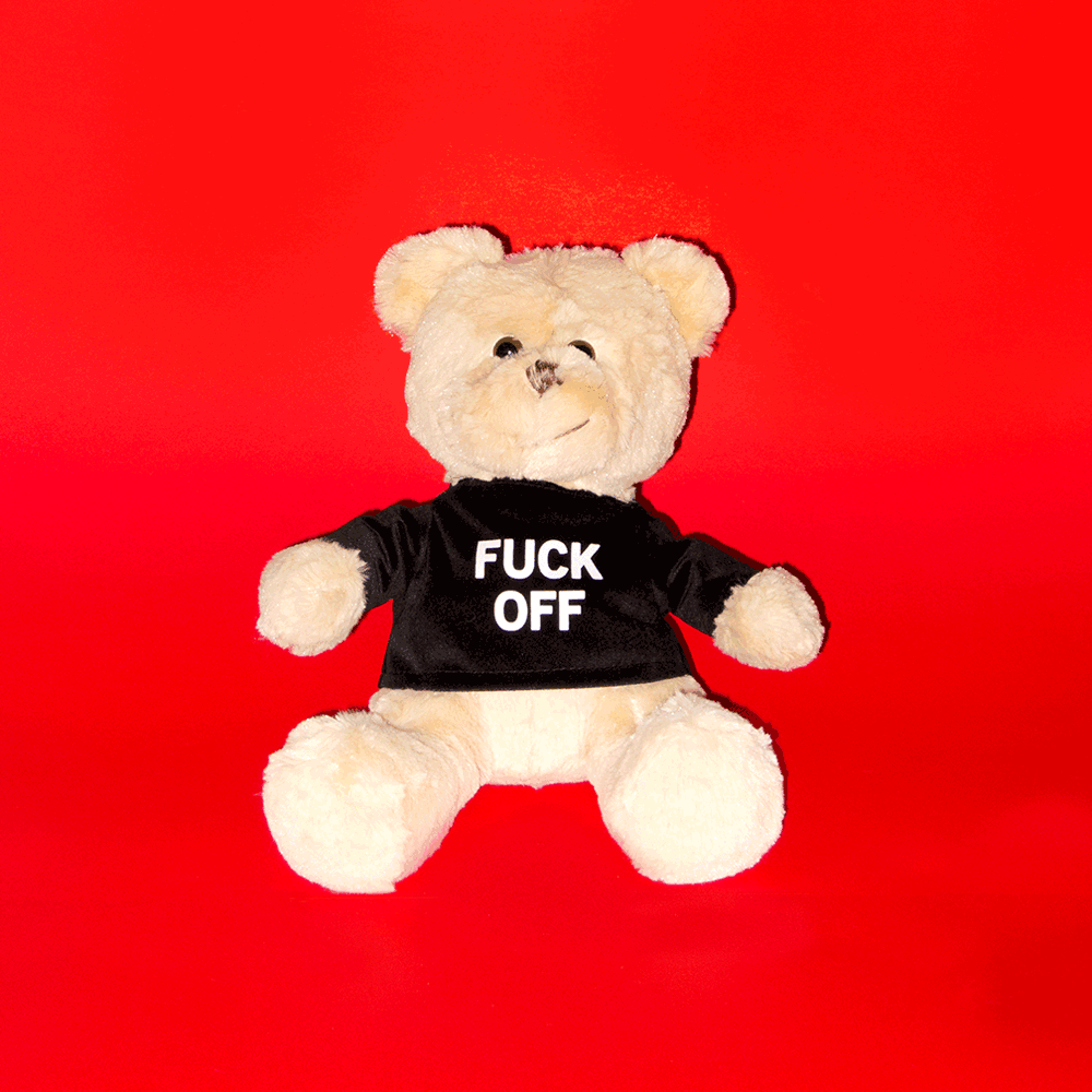 Animated gif of the official NO FUN® "Friendly" plush teddy bear waving.  The bear is wearing a velveteen shirt with "Fuck Off" print on front.