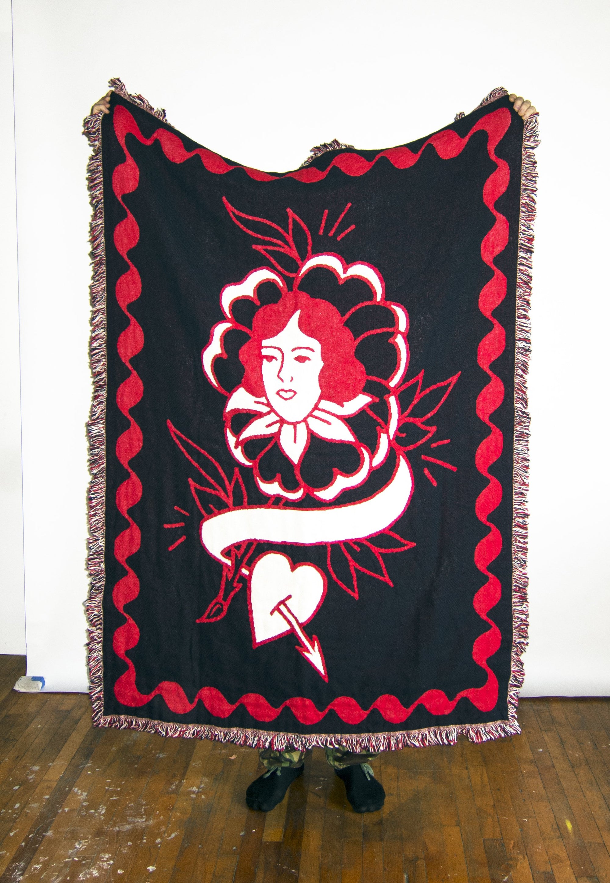 No Fun Press "Rose" woven blanket. Woven from 100% cotton in red, white, and black, at 48" x 68." Pictured here being held up beside a person to show scale