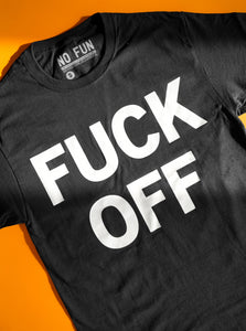 The "Fuck Off" T-Shirt by No Fun®. The t-shirt is black, and photographed against an orange background. The graphic that is found of the front of the t-shirt includes the phrase "FUCK OFF" written in white, in large capital block letters.