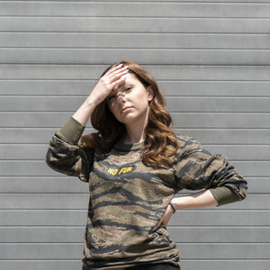 Woman standing in front of a garage door wearing the tiger camouflage "Invisible" longsleeve shirt.