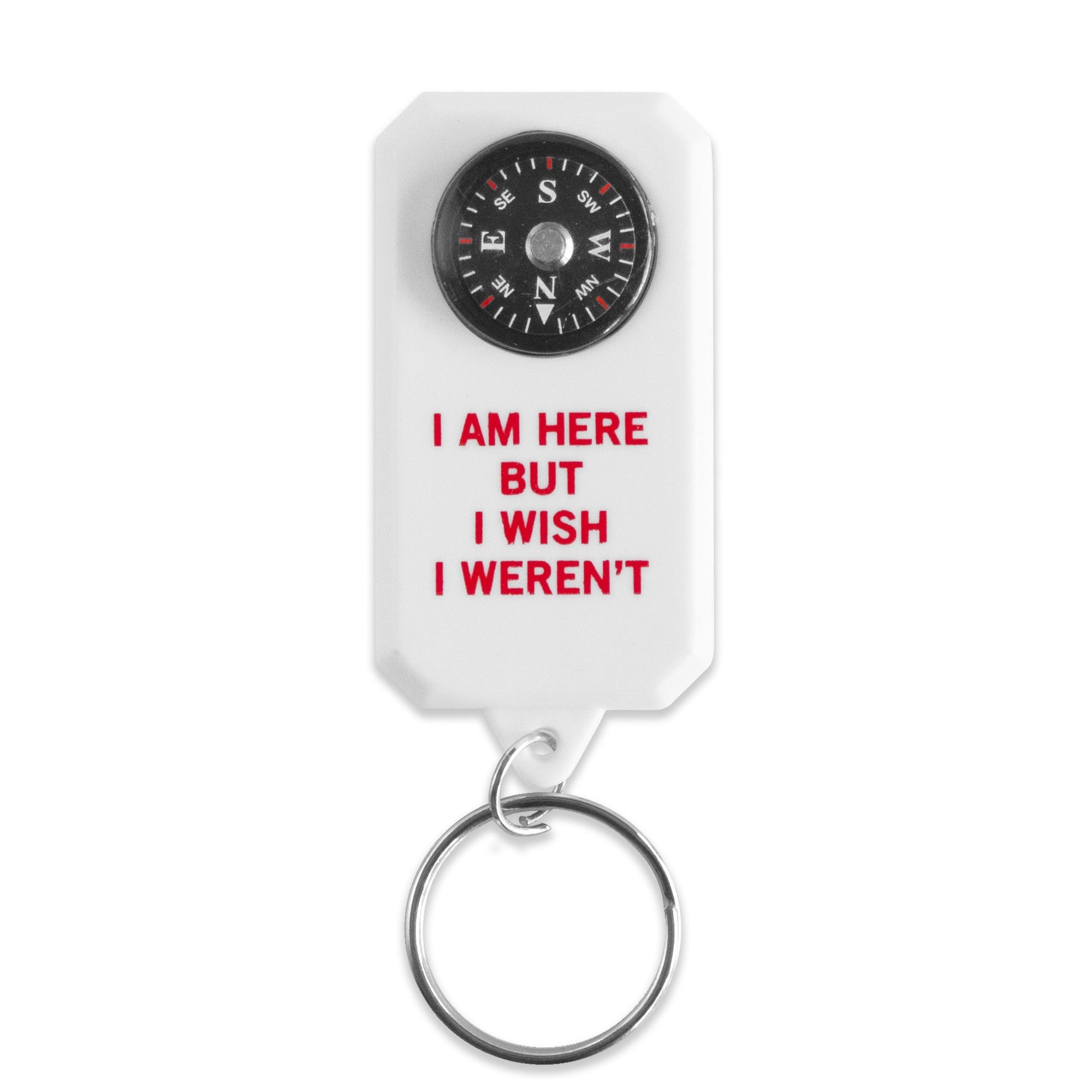 A photo of a keychain on a white background.  The keychain has a small functional compass near the top, and the phrase "I am here but I wish I weren't" is printed in red font underneath.