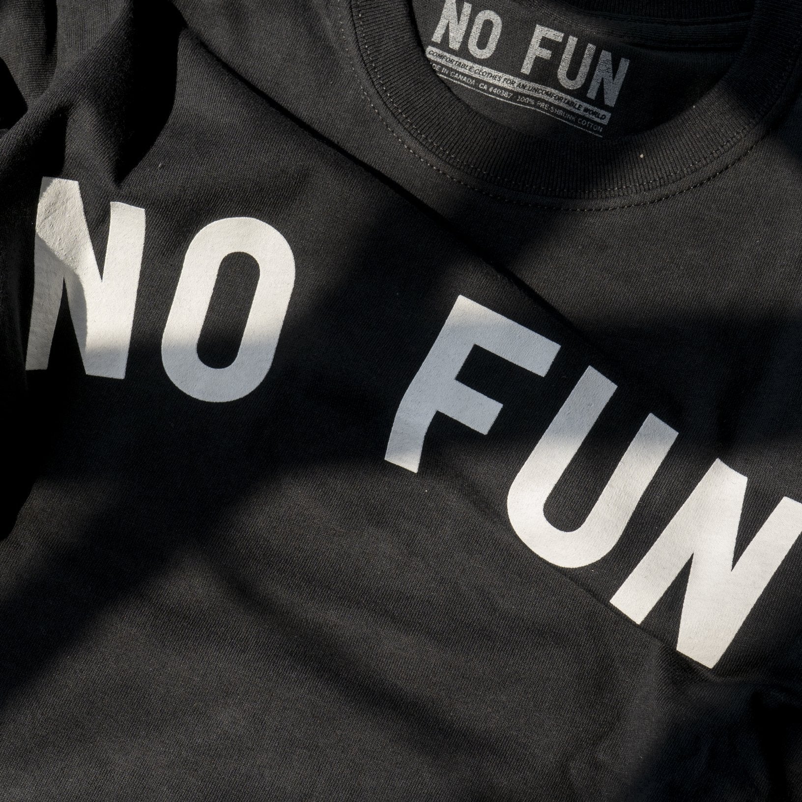 Detail of the No Fun® text across the classic t-shirt. Shirt is black, text is white.
