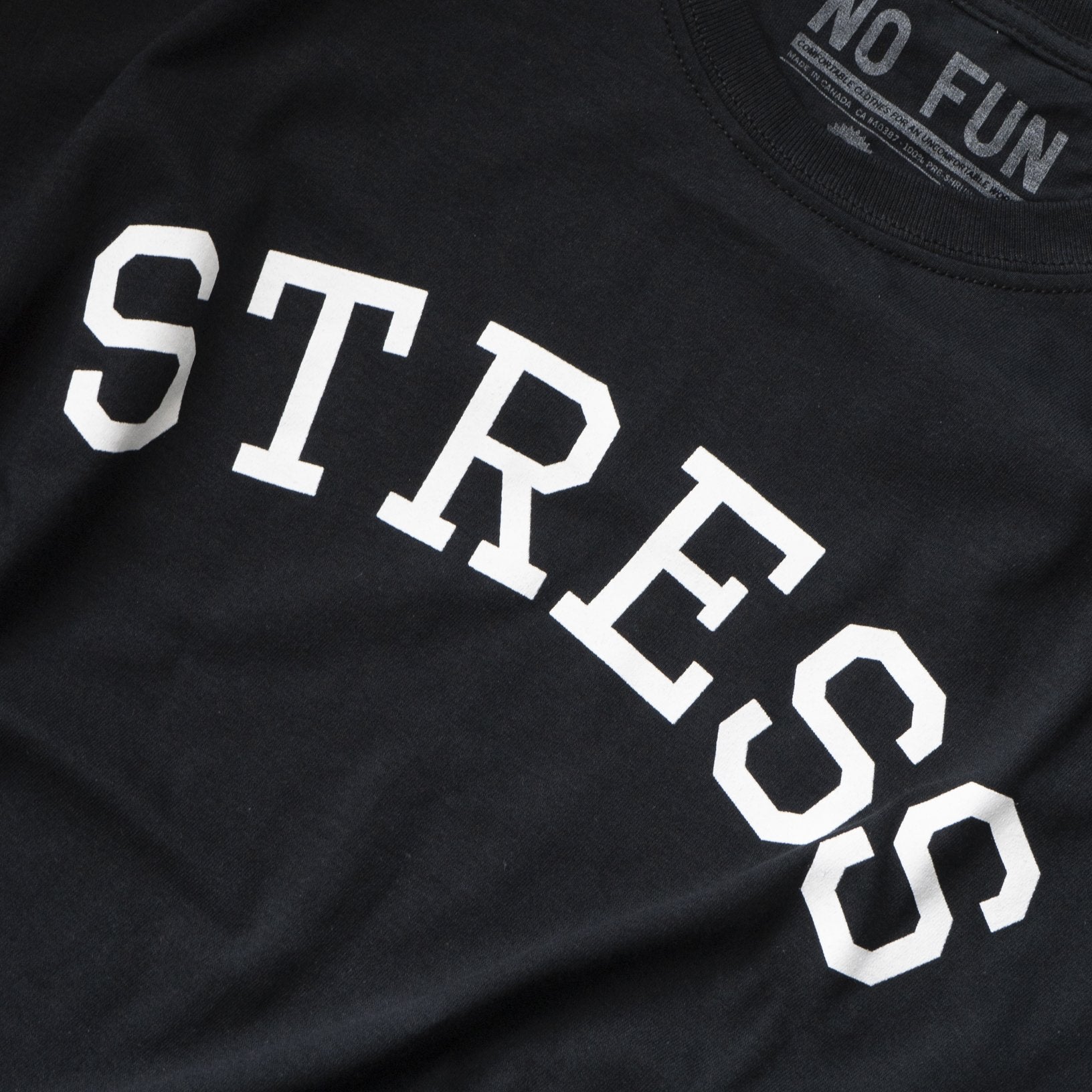 Detail photo of the original NO FUN® "STRESS" t-shirt. Shirt is black and features large white collegiate style text that reads "STRESS" across the front in an arc shape.
