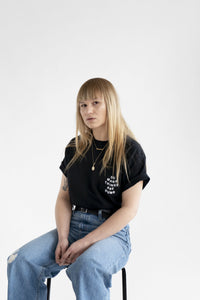 A female model wearing the original NO FUN® "So Many Things Are Dumb" Pocket tee, designed and printed in Toronto. T-shirt features front pocket and white text that reads "SO MANY THINGS ARE DUMB".